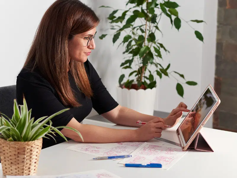 Mujer trabajando en un escritorio virtual con una tablet, interactuando con la pantalla táctil.